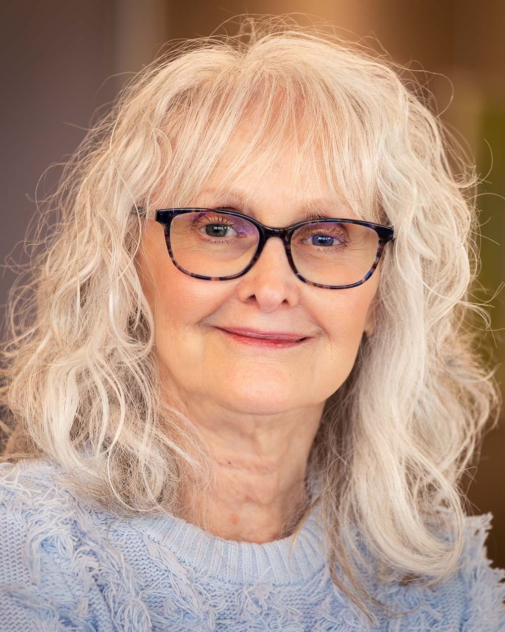 Portrait of a woman wearing glasses and a light blue sweater.
