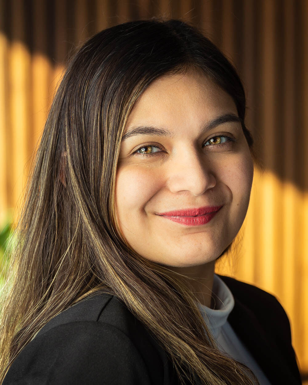 Portrait of Nabila Justiniano, a woman with dark brown hair wearing a white shirt and black jacket