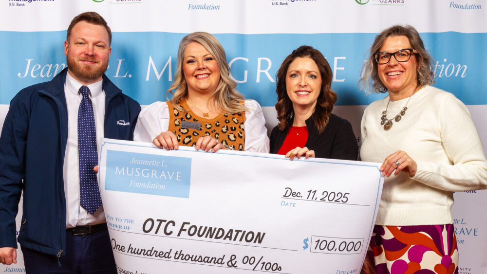 A man and three women pose with an oversized check in front of a white and blue background. The check is from the Jeannette L. Musgrave Foundation and written to OTC Foundation for $100,000. IDs from left to right: Cray Allred and Elizabeth Van Ness, OTC Foundation; Winter Kinne, CFO; and Michele Risdal-Barnes, Musgrave Foundation.