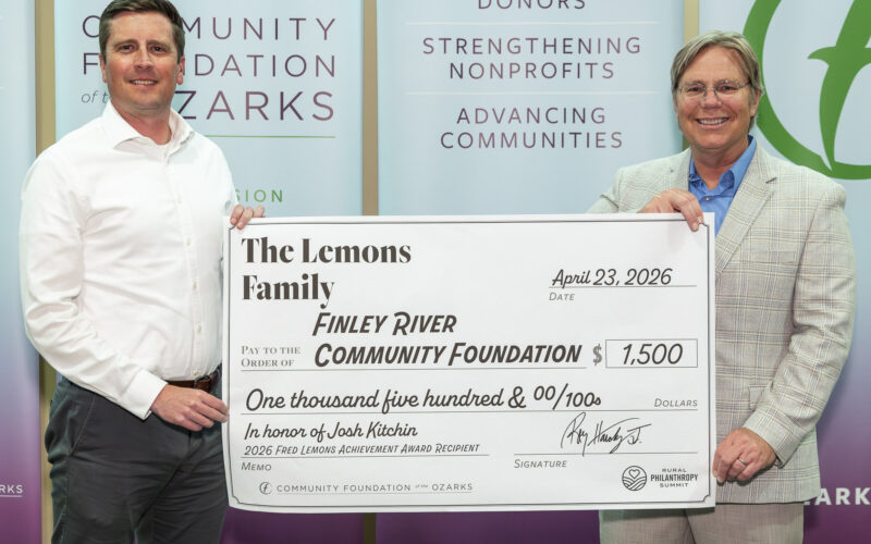 Two men — Josh Kitchin and Joe Kammerer — pose holding a large ceremonial check for $1,500 payable to the Finley River Community Foundation from the Lemons Family. The check references the 2026 Fred Lemons Achievement Award, with Community Foundation of the Ozarks banners behind them.