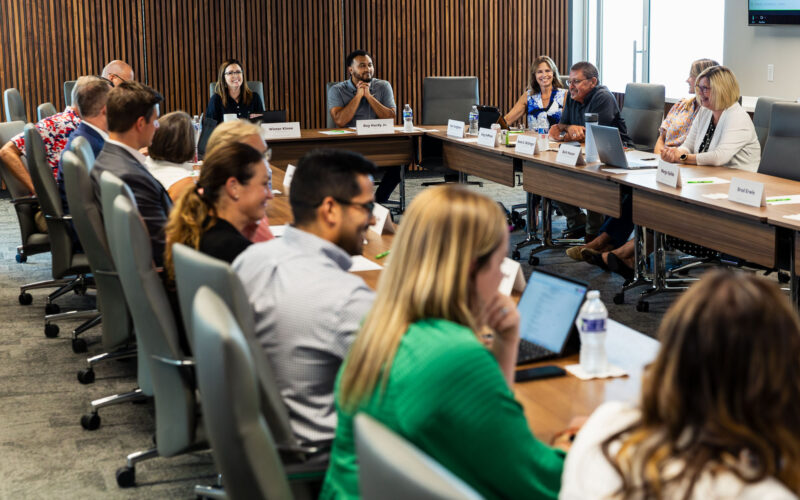 A group of people are seated around a board room table. The CFO's Board of Directors met for the first time in its new headquarters on Aug. 20, 2025.