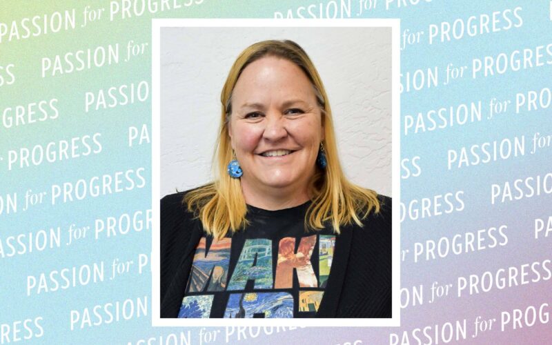 Portrait of Jennifer Jones, a woman wearing a black cardigan and a “Make Art” graphic T-shirt. Behind the portrait, Passion for Progress is repeated on a multicolored background.