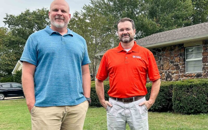 Two men stand outside of a house in Joplin.