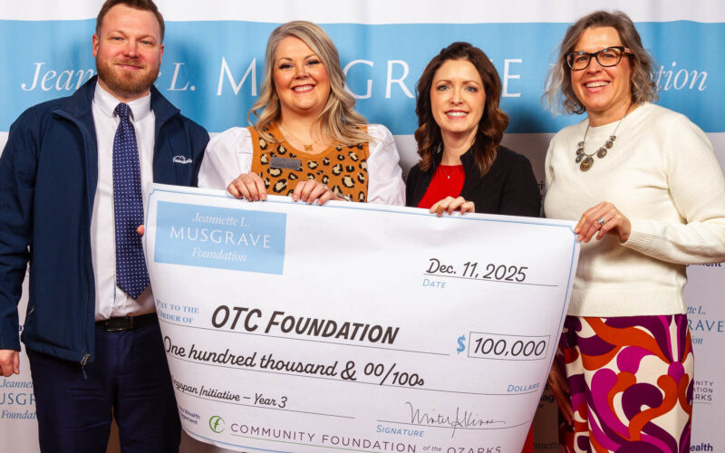 A man and three women pose with an oversized check in front of a white and blue background. The check is from the Jeannette L. Musgrave Foundation and written to OTC Foundation for $100,000. IDs from left to right: Cray Allred and Elizabeth Van Ness, OTC Foundation; Winter Kinne, CFO; and Michele Risdal-Barnes, Musgrave Foundation.