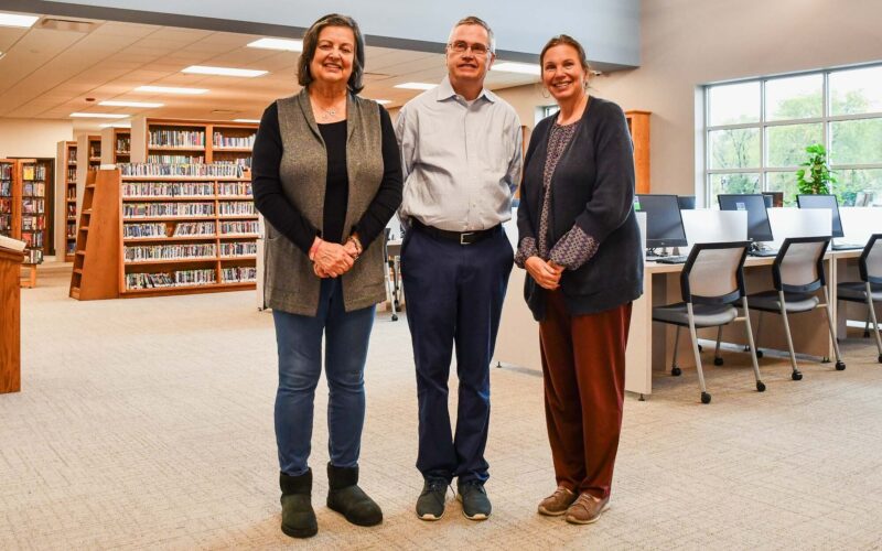 A woman, a man and a woman pose as a group in the middle of a new library in Houston, Missouri.
