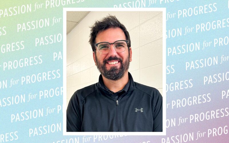 Portrait of Will Darter, a man wearing glasses and a black quarter-zip shirt, framed against a pastel background patterned with the words “Passion for Progress.”