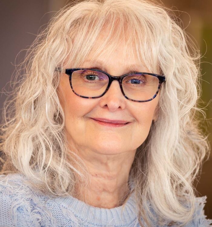 Portrait of a woman wearing glasses and a light blue sweater.