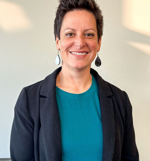 A portrait of a woman, smiling and wearing a dark-colored jacket.