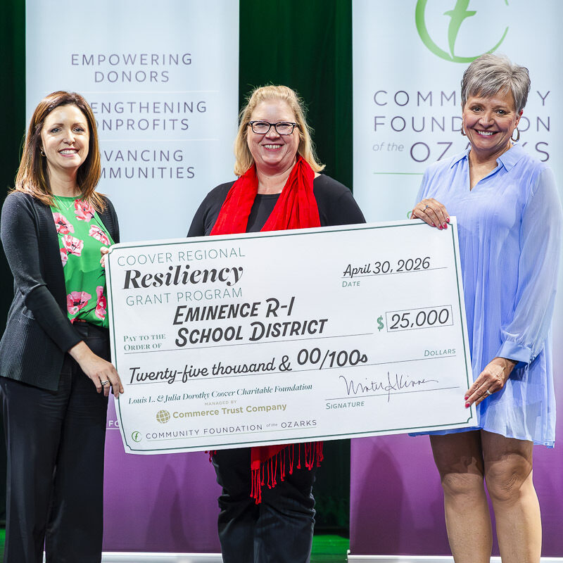Three women pose with an oversized grant check for the Coover Regional Resiliency Grant Program. The check is dated April 30, 2026, and is made out to Eminence R-I School District for $25,000. The check also features graphics for the Coover Charitable Foundation, Commerce Trust Company and the Community Foundation of the Ozarks.